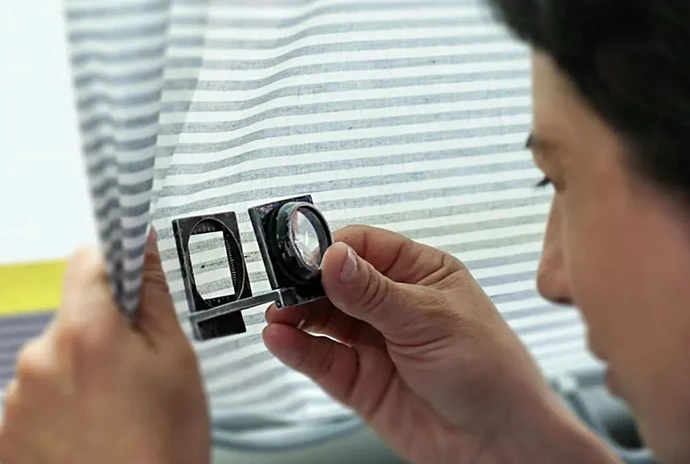 男人正在拿著放大鏡檢查面料